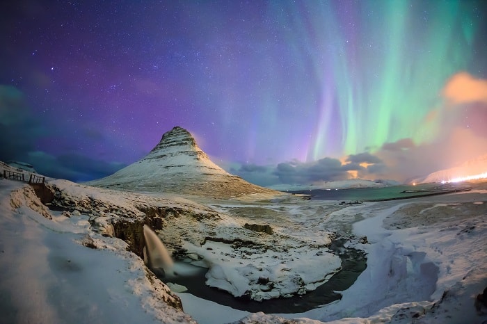 Spectacular northern lights appear over Mount Kirkjufell and waterfall in Iceland.