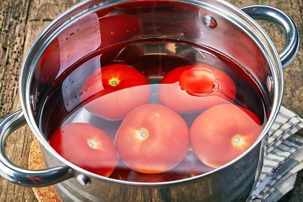 ripe tomatoes in a pot of water