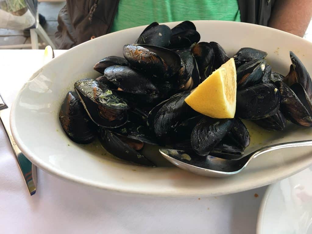 A plate of steamed mussels with lemon garnish