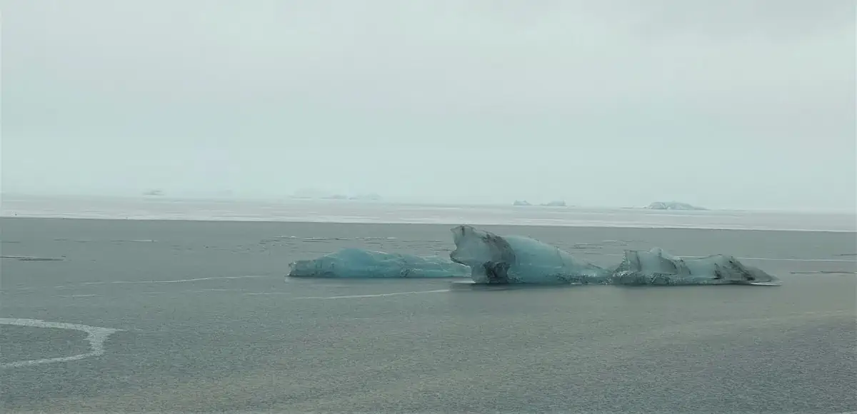 Jökulsarlon Glacier Lagoon - With an iceberg floating on the water.