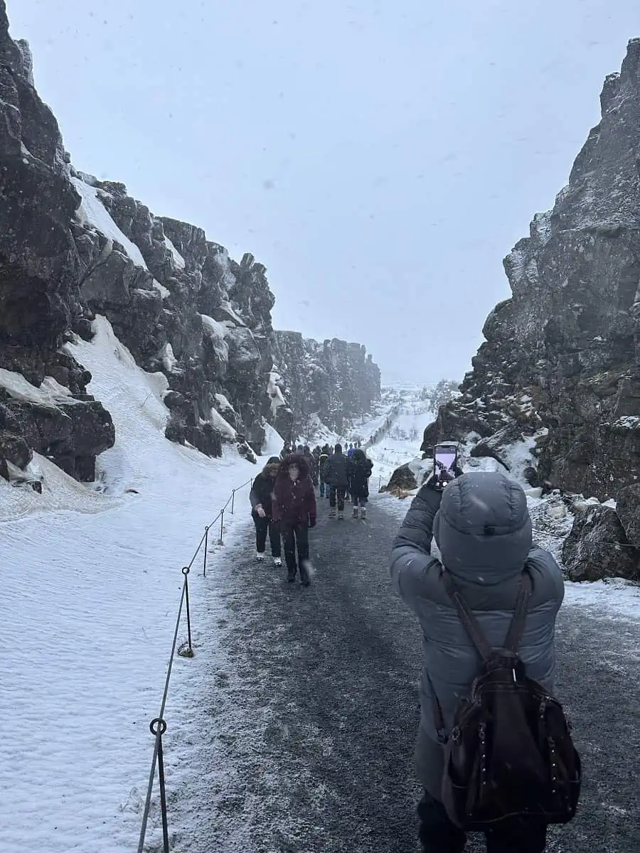 Iceland in January - People walking up and down the Silfra Fissure on an icy path in the snow.