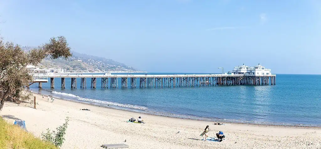 A long expanse of Malibu Beach with Malibu Pier in the distance