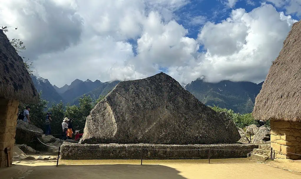 A Large Granite Stone on An Alter of many smaller stones with the Mountains and Clouds in the Backgournd. The Sacred Rock at Machu Picchu