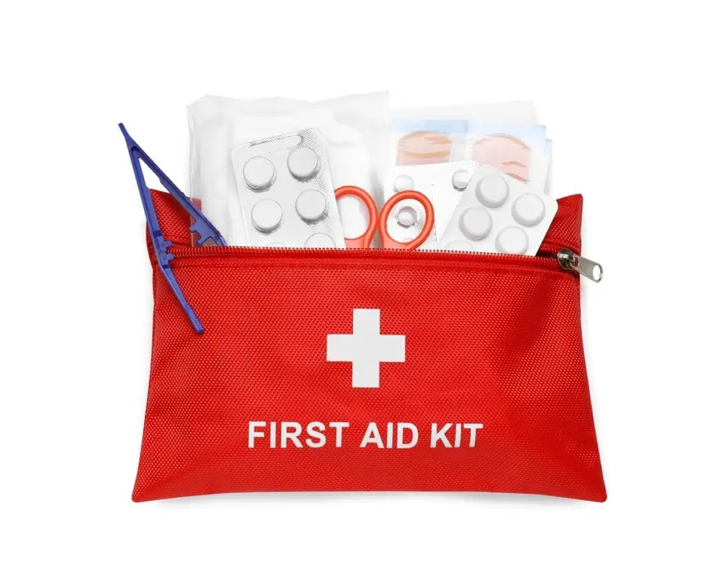 Red first aid kit with scissors, pills, plastic forceps and medical plasters isolated on white, top view