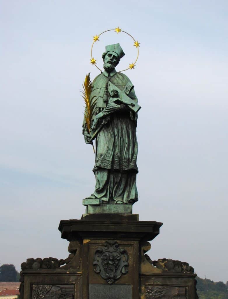 Bronze statue with a golden halo of stars of an important church elder on the Charles Bridge in Prague -  Visit Prague