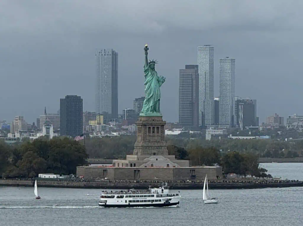 New York City Before A Cruise: Sailing From the Red Hook Cruise Terminal 4 Iconic Statue of Liberty with Manhattan skyscrapers in the background, symbolizing New York City’s freedom and vibrant urban life.
