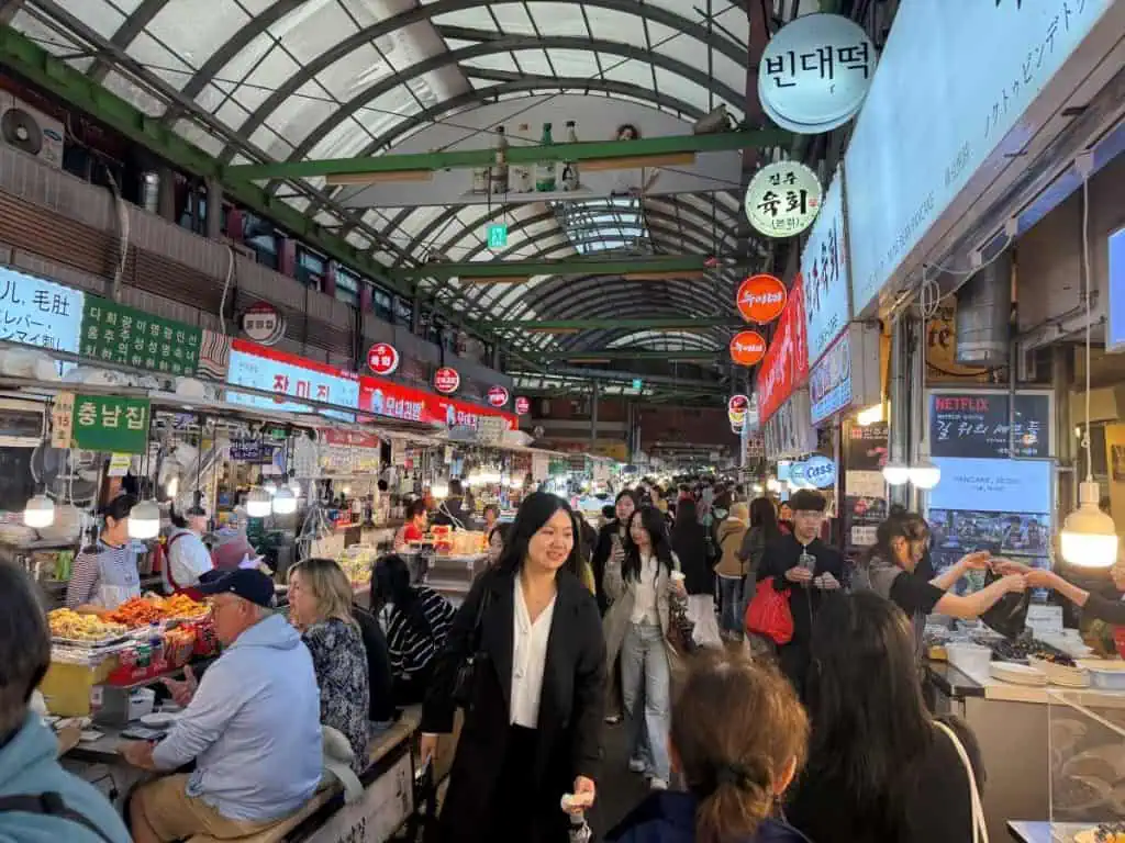 6 Days in Seoul: Royal Palaces, Korean BBQ, Hanbok, and the Unforgettable DMZ 5 Gwangjang market in Seoul with vendors, shoppers, and colorful signs in Korean, capturing the lively atmosphere of South Korea's markets.